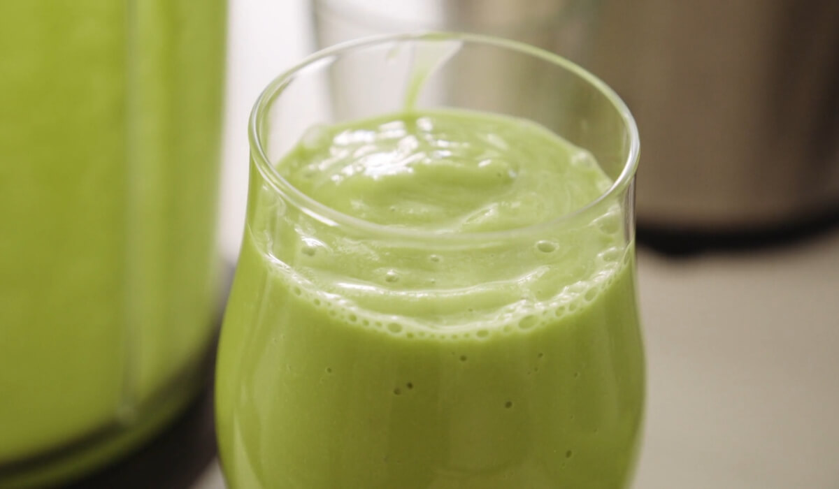 Staklena čaša sa zelenim smutijem.